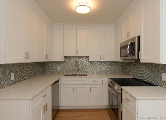 kitchen with white cabinets, decorative backsplash, stainless steel appliances, and sink