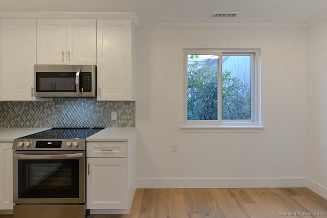 kitchen with white cabinets, backsplash, stainless steel appliances, and light hardwood / wood-style floors