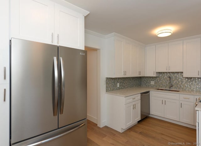 kitchen featuring white cabinetry, sink, stainless steel appliances, tasteful backsplash, and light hardwood / wood-style flooring