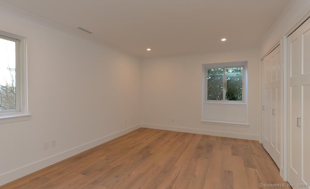 empty room featuring light wood-type flooring and ornamental molding