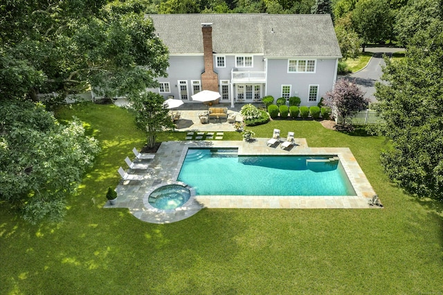 back of house with a pool with connected hot tub, a patio area, a yard, and a chimney