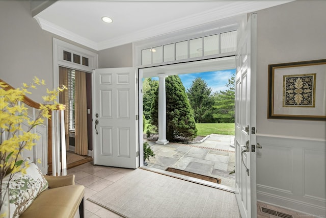 tiled foyer featuring wainscoting, visible vents, crown molding, and a decorative wall