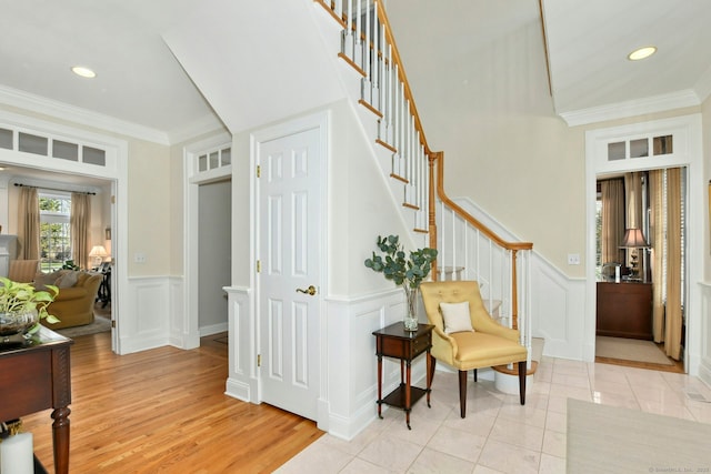 interior space with light tile patterned floors, stairs, crown molding, a decorative wall, and recessed lighting