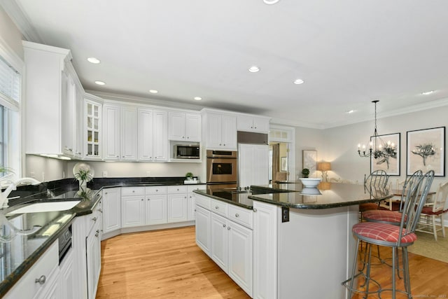 kitchen with a breakfast bar area, stainless steel appliances, crown molding, light wood-type flooring, and a sink