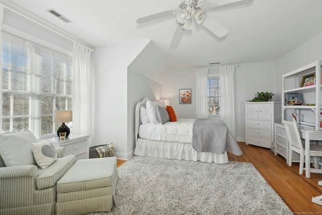 bedroom featuring ceiling fan, wood finished floors, visible vents, and baseboards