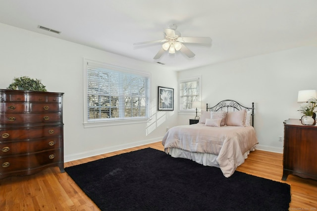 bedroom with ceiling fan, light wood-style flooring, visible vents, and baseboards