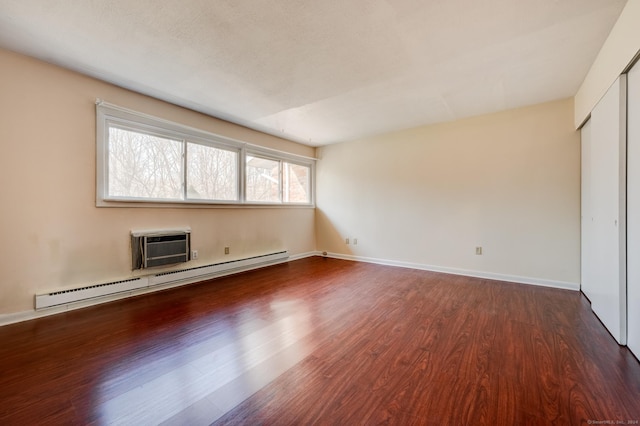 interior space featuring an AC wall unit, dark wood-type flooring, and a baseboard radiator