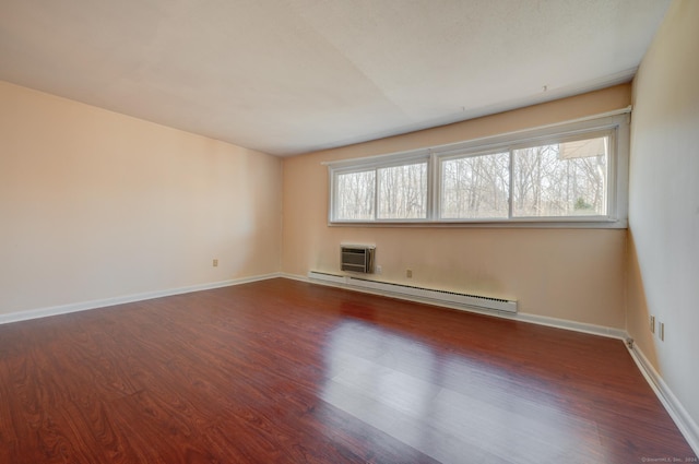 unfurnished room featuring a baseboard heating unit, plenty of natural light, and dark wood-type flooring