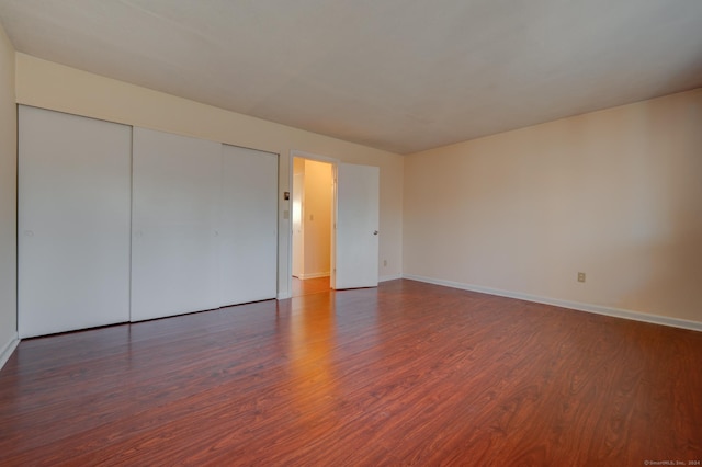 unfurnished bedroom with dark hardwood / wood-style floors and a closet