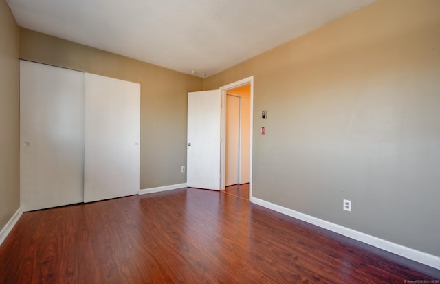 unfurnished bedroom with dark wood-type flooring and a closet