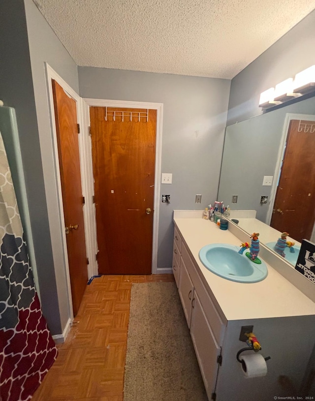 bathroom with vanity, parquet floors, and a textured ceiling