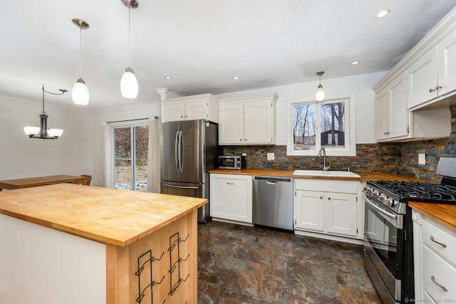 kitchen with wood counters, appliances with stainless steel finishes, pendant lighting, and sink