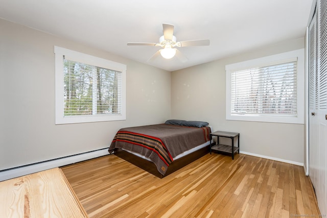 bedroom with wood-type flooring, ceiling fan, and a baseboard heating unit