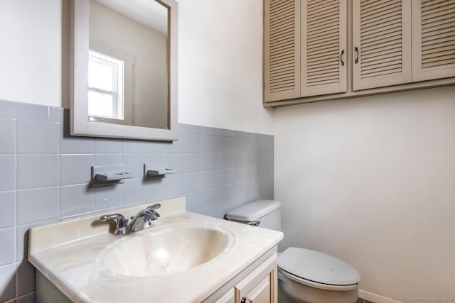 bathroom with vanity, toilet, and tile walls