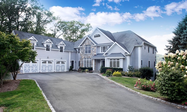 view of front facade featuring aphalt driveway, stone siding, and a garage