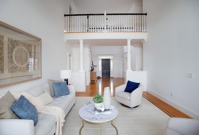 living area with a high ceiling, wood finished floors, and ornate columns