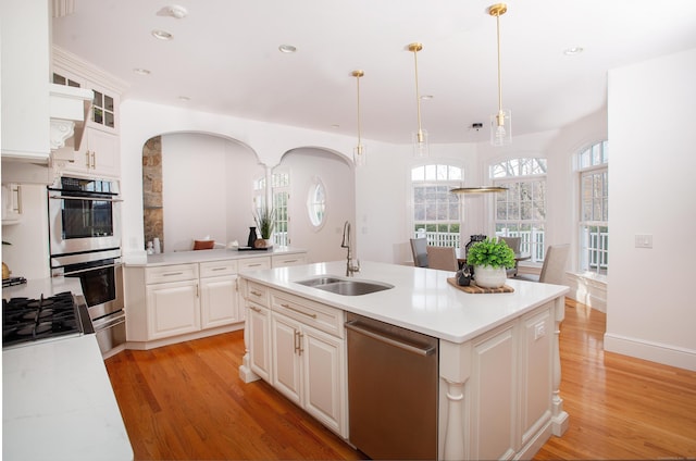 kitchen with a sink, stainless steel appliances, light wood-style floors, and light countertops