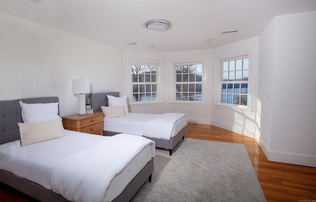 bedroom with visible vents, baseboards, and wood finished floors