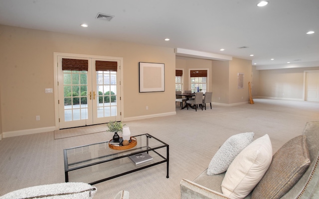 living room featuring a wealth of natural light, visible vents, and light colored carpet