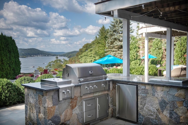 view of patio / terrace with grilling area, a water and mountain view, and area for grilling