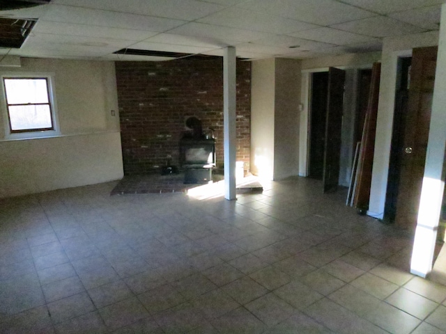 basement with a paneled ceiling and a wood stove