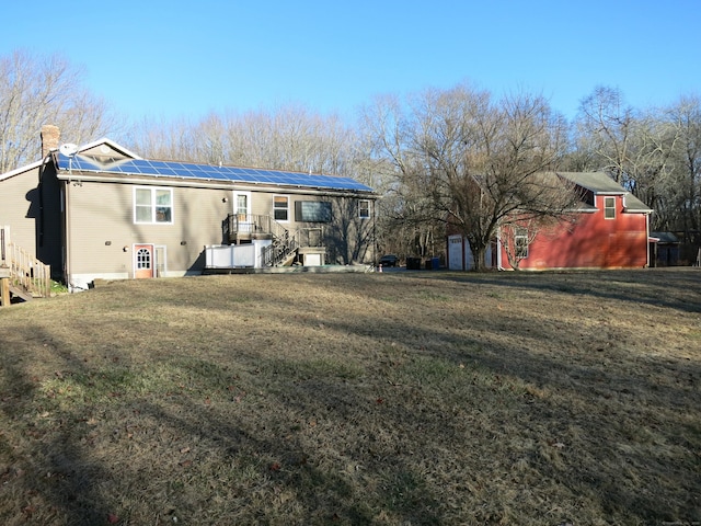 back of house with a lawn, a storage shed, and solar panels