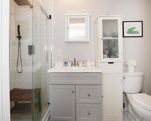 bathroom featuring vanity, a shower with shower door, and toilet