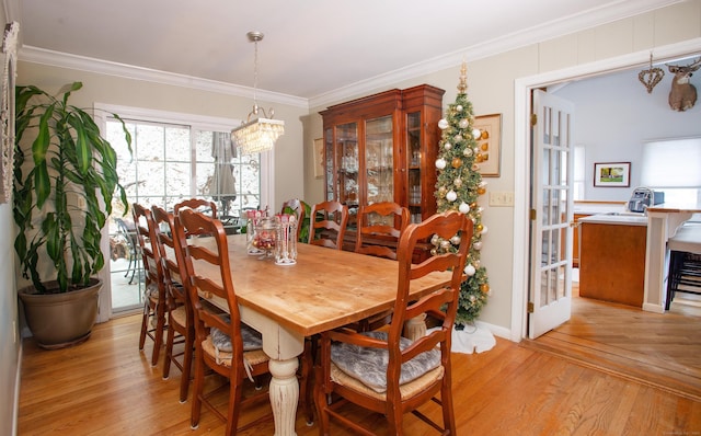 dining space featuring light wood-type flooring, an inviting chandelier, and ornamental molding