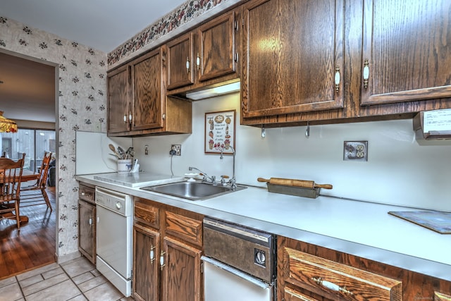 kitchen featuring dishwasher, light tile patterned floors, dark brown cabinets, and sink