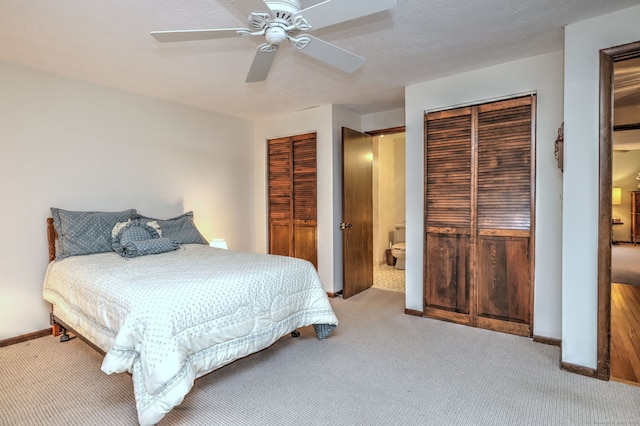 bedroom with ceiling fan, light colored carpet, and two closets