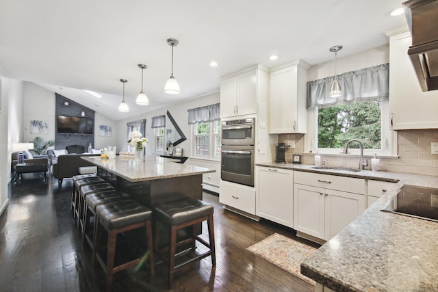 kitchen with white cabinetry, sink, dishwashing machine, and decorative light fixtures