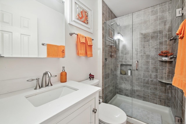 bathroom featuring vanity, toilet, and a shower with shower door