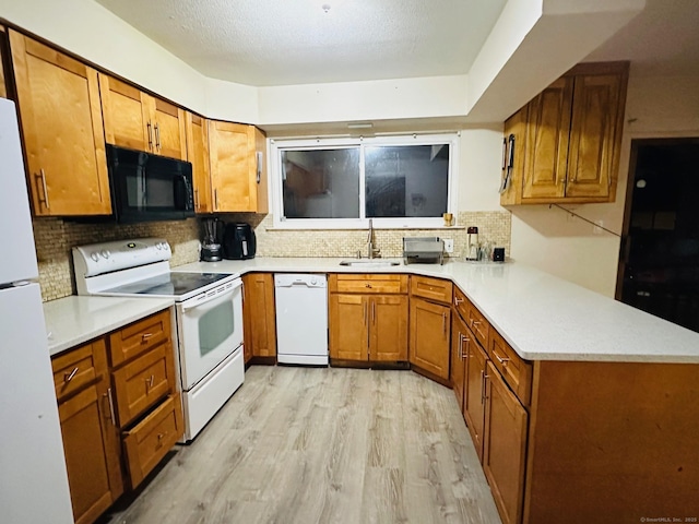 kitchen with decorative backsplash, white appliances, light hardwood / wood-style flooring, and sink