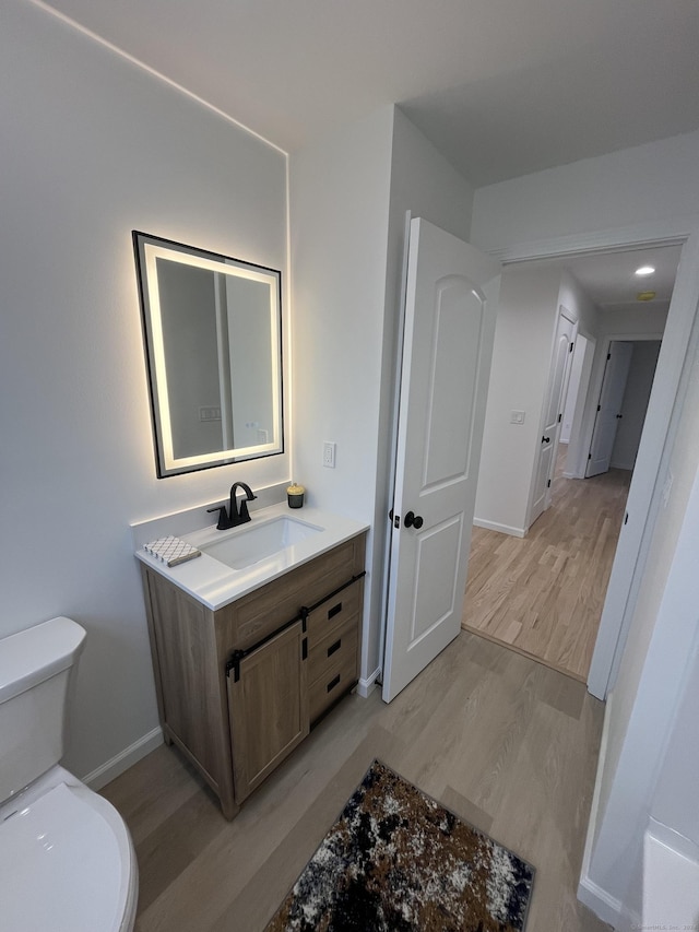 bathroom with toilet, vanity, and hardwood / wood-style flooring