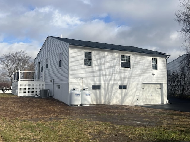 rear view of house featuring central air condition unit, a wooden deck, and a garage