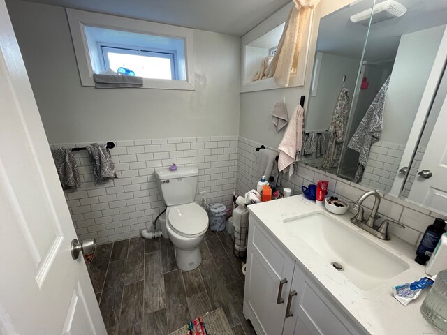 bathroom featuring vanity, toilet, and tile walls