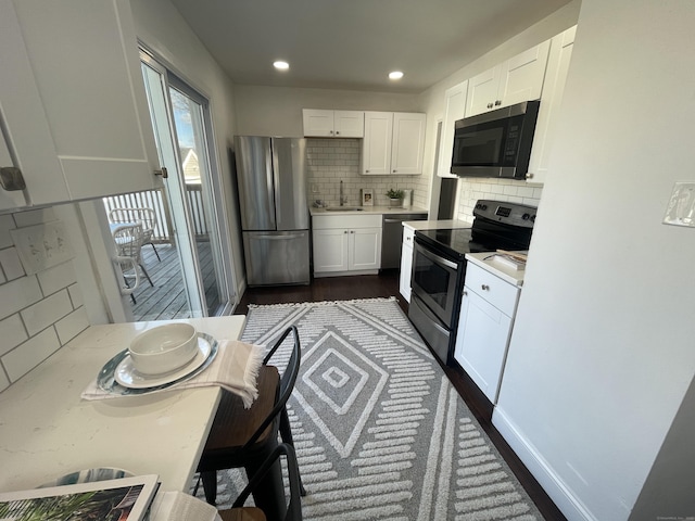 kitchen featuring sink, dark hardwood / wood-style floors, backsplash, white cabinets, and appliances with stainless steel finishes