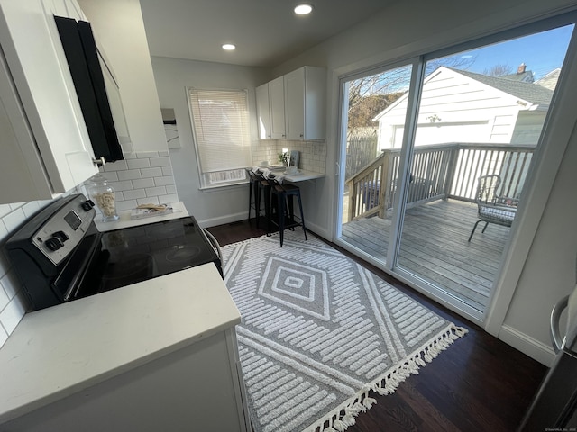 kitchen featuring backsplash, white cabinetry, electric range, and dark hardwood / wood-style floors