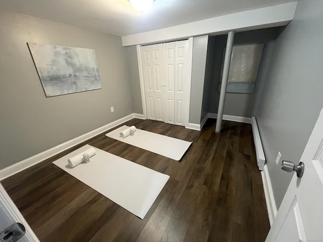 unfurnished bedroom featuring dark hardwood / wood-style floors, a baseboard heating unit, and a closet