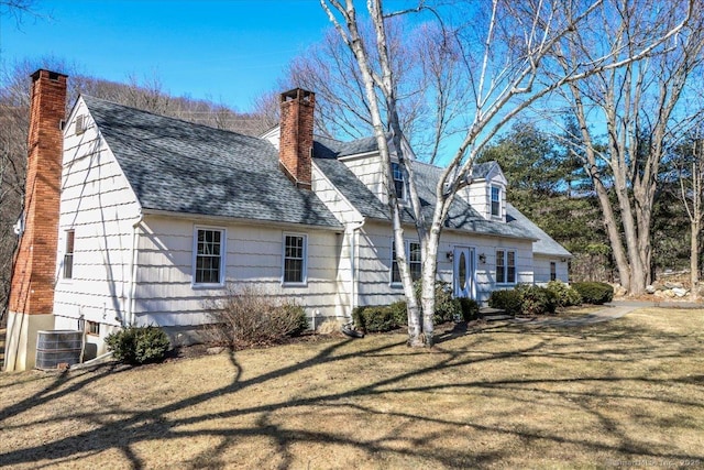 back of house featuring a yard, cooling unit, roof with shingles, and a chimney