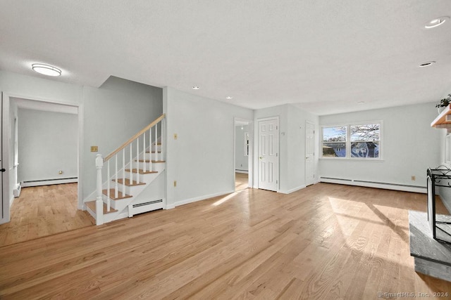 unfurnished living room featuring a baseboard heating unit and light wood-type flooring