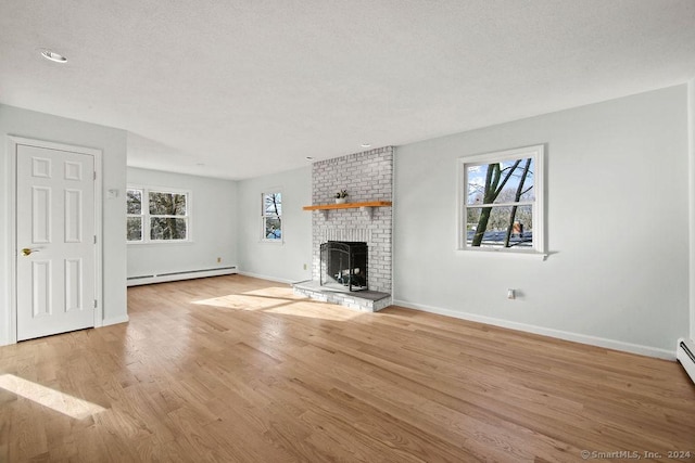 unfurnished living room featuring baseboard heating, a brick fireplace, and light wood-type flooring