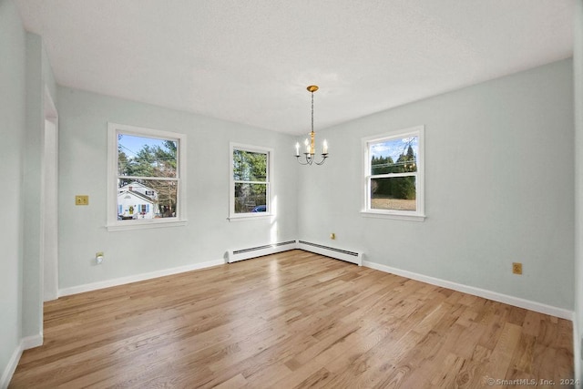 unfurnished dining area with a baseboard heating unit, a wealth of natural light, light hardwood / wood-style floors, and a chandelier