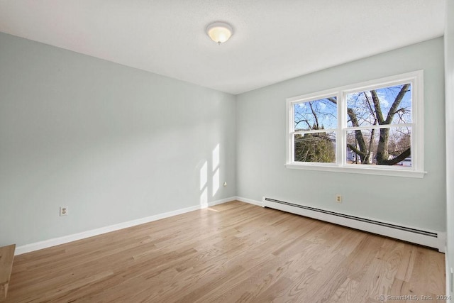 spare room with baseboard heating and light hardwood / wood-style floors