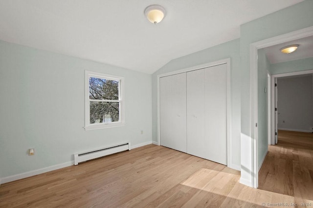 unfurnished bedroom with a baseboard radiator, light hardwood / wood-style floors, a closet, and vaulted ceiling