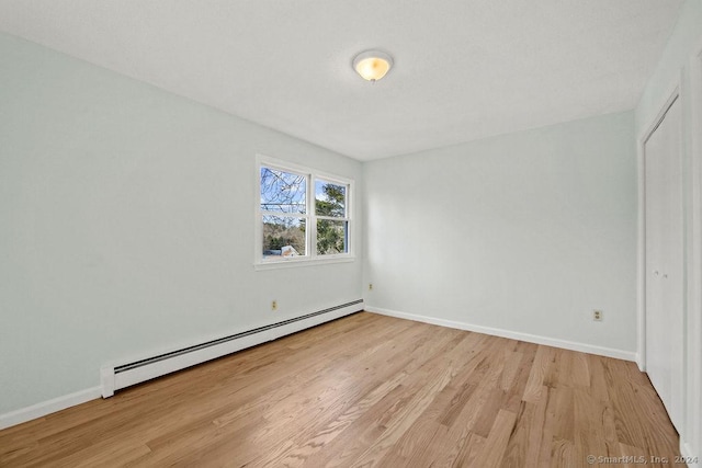 unfurnished room featuring baseboard heating and light hardwood / wood-style flooring