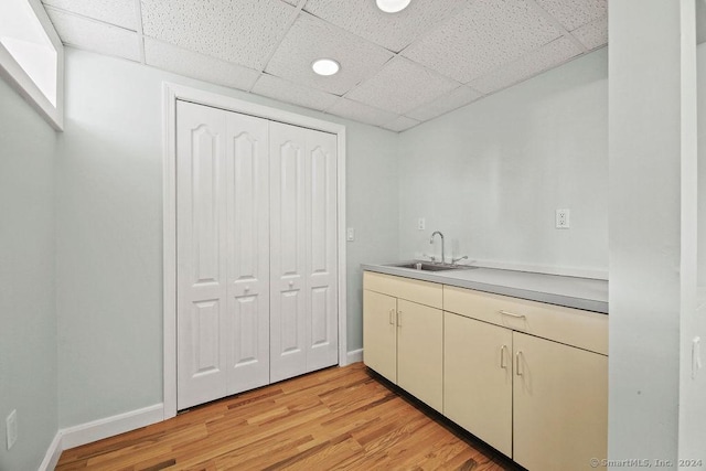 kitchen featuring a drop ceiling, sink, and light hardwood / wood-style floors