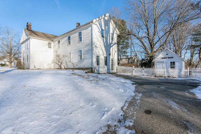 view of snowy exterior with a garage and an outdoor structure