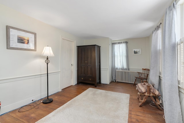 sitting room with radiator heating unit and dark wood-type flooring