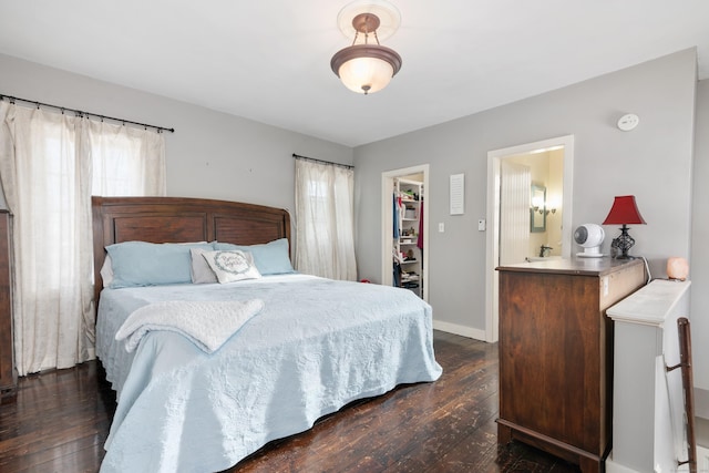 bedroom with a closet, dark hardwood / wood-style flooring, a spacious closet, and multiple windows